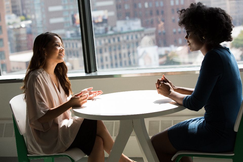Zwei Frauen im Gespräch an einem runden Tisch